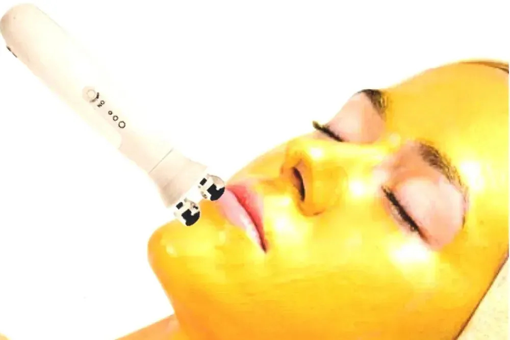 Woman receiving signature facial treatment with a specialized device for glowing skin enhancement.